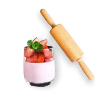 A parfait with berries in a glass near a rolling pin.