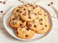 Un plato de galletas con chispas de chocolate con bocaditos de chocolate esparcidos alrededor de servilletas.