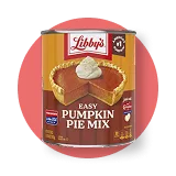 Front view photograph of an orange and brown can of Libby’s Easy Pumpkin Pie Mix on a distressed brown circle . It has the Libby’s name and red and white logo above a brown box displaying the product name in white and a whole pumpkin pie beside a gold serving spatula.