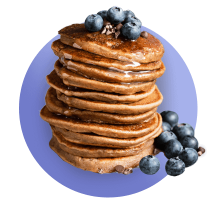 A tall stack of pancakes topped with fresh blueberries that spill off to the side against a royal blue gradient circle.