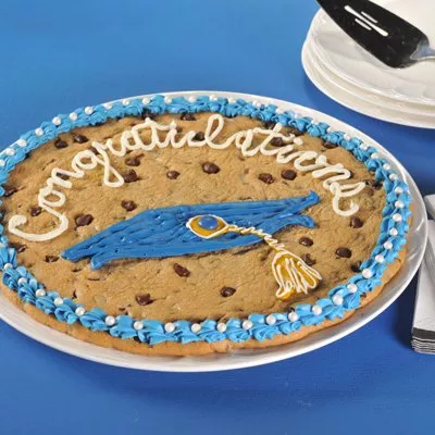 Photo of chocolate-chip cookie cake iced "Congratulations" with blue mortarboard and yellow tassel