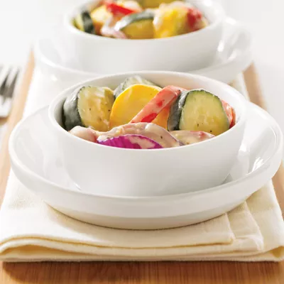Photograph: two white bowls with creamy mixed vegetable salad on folded napkin