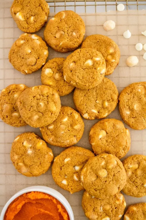 Fotografía: galletas con chispas de chocolate blanco sobre rejilla y un cuenco de puré naranja