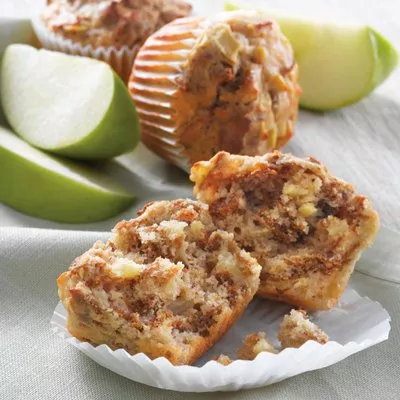 Photograph of broken nut-studded muffin halves with whole muffins and green apple slices