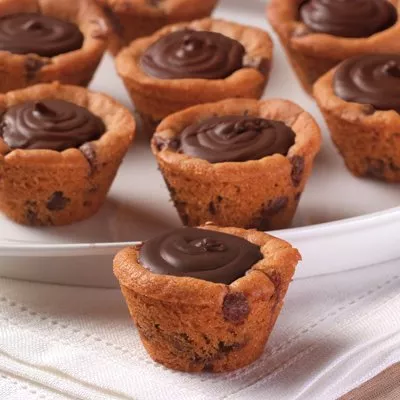 Photograph of mini chocolate chip cookie cups topped with swirled chocolate ganache