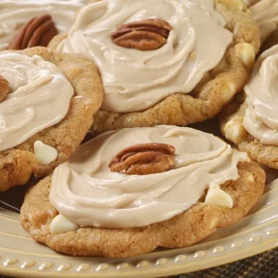 Frosted cookies topped with pecan halves, close-up