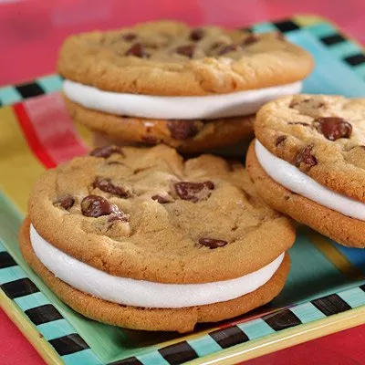 Photograph: three chocolate-chip cookie sandwiches with white filling on colorful striped plate