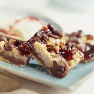 Close-up photo of chocolate-drizzled nut bars on blue plate with scoop of ice cream