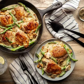 Pollo cremoso en una sartén con espárragos y champiñones